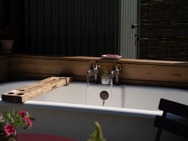 A bathtub with faucets and a wooden plank at Hurdlemakers Hut in Piddletrenthide