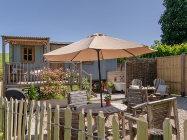 A garden with a table, chairs, and an umbrella at Spindleberry Hut in Piddletrenthide