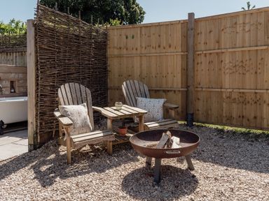 An outdoor seating area with chairs and a fire pit at Spindleberry Hut in Piddletrenthide