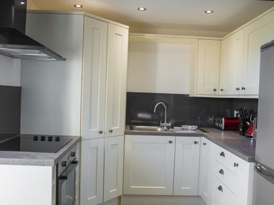 A kitchen with white cabinets a sink a stove a toaster and a refrigerator at The Hidden Place in Watermillock near Pooley Bridge