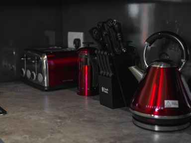 A kitchen counter with a red toaster red kettle a red French press and a knife block at The Hidden Place in Watermillock near Pooley Bridge