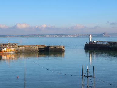 A harbor with a lighthouse and fishing boat visible near a pier at Bodillys Cottage in Newlyn