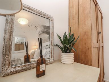 A bedroom with a wooden cabinet and a mirror at Bodillys Cottage Newlyn