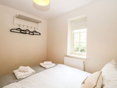 A bedroom with a bed towels on the bed a window and hangers on a wall at 30 Burtons Mill in Stalham