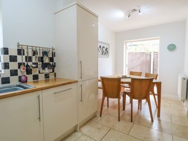 A kitchen with wooden dining table and chairs alongside cabinetry and kitchen utensils at 30 Burtons Mill in Stalham