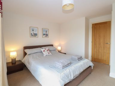 A bedroom with a double bed two bedside tables with lamps and two framed pictures on the wall at 30 Burtons Mill in Stalham