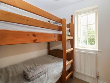 A wooden bunk bed with folded towels on the bottom bed next to a window and radiator at 30 Burtons Mill in Stalham