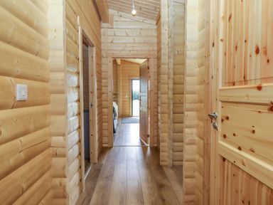 A wooden hallway with multiple doors and a light bulb hanging at Primrose Lodge in Hittisleigh