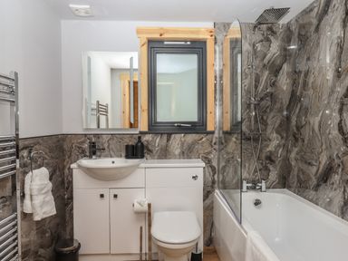 A bathroom with a sink toilet and bathtub with shower at Primrose Lodge in Hittisleigh