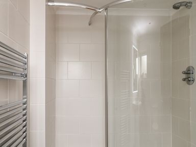 A tiled shower area with a glass door and a metal towel rack at Looe Island View in Downderry