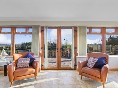 A room with two brown armchairs and glass doors leading to an outdoor area at Rose Cottage in Muff County Donegal
