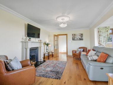 A living room with leather armchairs a sofa a fireplace and a mounted TV at Rose Cottage in Muff County Donegal