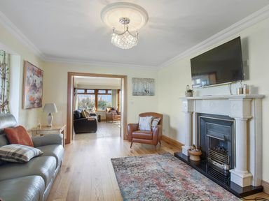 A living room with leather sofas a fireplace and a wall-mounted television at Rose Cottage in Muff County Donegal