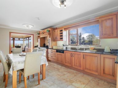 A kitchen with wooden cabinets and a dining table with chairs at Rose Cottage in Muff County Donegal