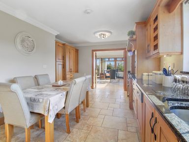 A kitchen and dining area with wooden cabinets and a table with six chairs at Rose Cottage in Muff County Donegal