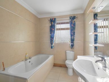 A bathroom with a bathtub a toilet and a sink with a mirror at Rose Cottage in Muff County Donegal