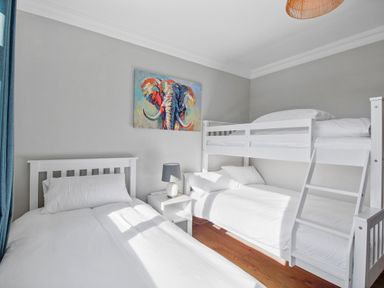 A bedroom with a single bed a bunk bed a nightstand with a lamp and an elephant painting on the wall at Rose Cottage in Muff County Donegal