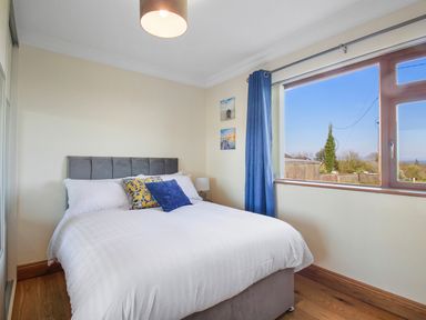 A bedroom with a bed and two blue pillows beside a window with blue curtains at Rose Cottage Muff County Donegal