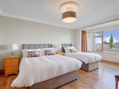 A bedroom with two beds bedside tables lamps and a large window at Rose Cottage in Muff County Donegal