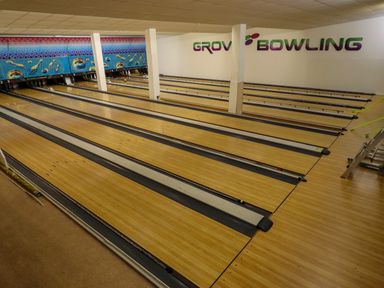 An indoor bowling alley with multiple bowling lanes and pins at the end at Grove Cottage in Leominster