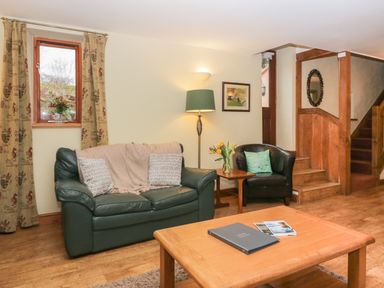 A sitting room with a green sofa and chair near a staircase at Winder Barn in Askham Cumbria