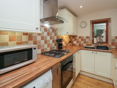 A kitchen with a microwave oven gas stove sink and wooden countertops at Winder Barn in Askham Cumbria
