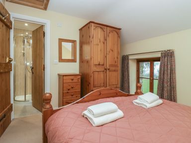 A bedroom with a wooden bed and furniture and white towels on the bed at Winder Barn in Askham Cumbria