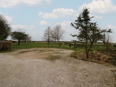 Gravel area with trees and grass under a partly cloudy sky at Winder Barn in Askham Cumbria