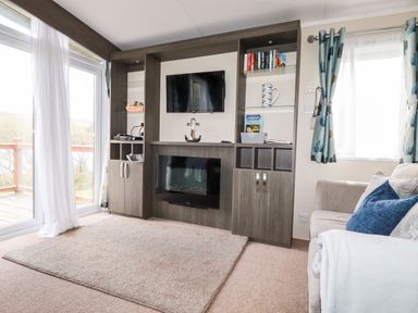 A living room with a mounted tv and electric fireplace between built-in shelves and cabinets at Lake View 10 in Par