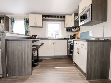 A kitchen with a window above the sink cabinets a microwave and oven and two bar stools at Lake View 10 in Par