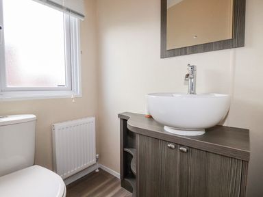 A bathroom with a toilet a sink with cabinet and a window at Lake View 10 in Par