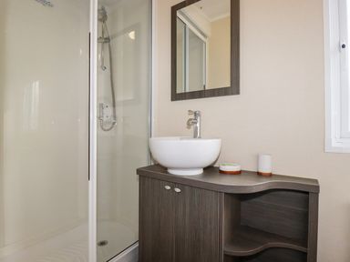 A bathroom with a shower enclosure a sink on a wooden cabinet and a mirror on the wall at Lake View 10 in Par