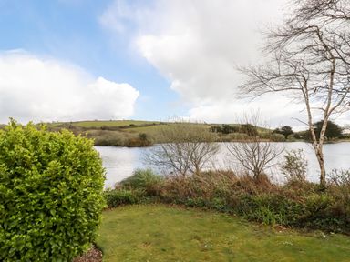 A lake with bushes and trees on the shore with grassy hills and sky in the background at Lake View 10 in Par