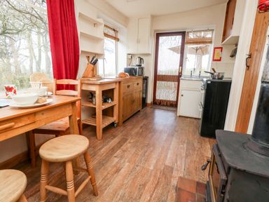 A kitchen with wooden furniture a stove a door with a beaded curtain and kitchen appliances at Eweleaze in West Bexington