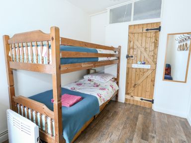 A bedroom with wooden bunk beds a wooden door and a wall mirror at Eweleaze in West Bexington