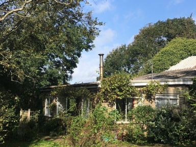A stone house surrounded by trees and shrubs at Eweleaze in West Bexington