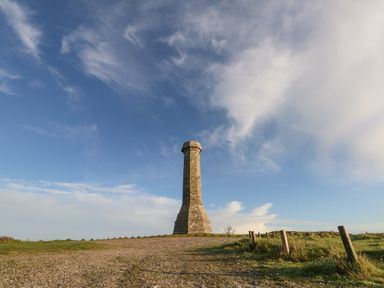 A stone monument on a hill with a gravel path and grassy surroundings at Eweleaze in West Bexington