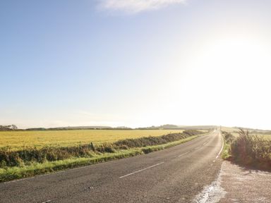 A road running alongside fields under a clear sky at Eweleaze in West Bexington