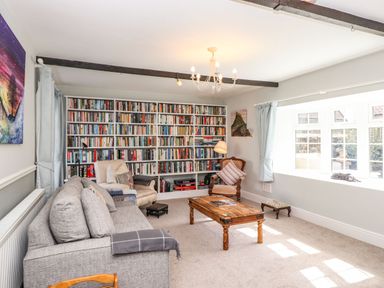 A living room with a large bookshelf two armchairs a wooden coffee table and a grey sofa at West Farm Cottage in Longhorsley