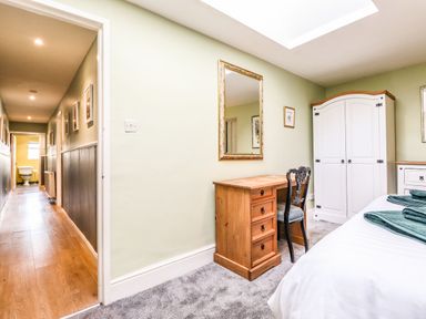 A bedroom with a wooden desk and chair white wardrobe and bed with folded towels at West Farm Cottage in Longhorsley
