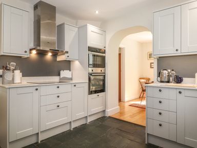 A kitchen with white cabinets, stainless steel oven and hood, utensils, kettle and coffee press at High Stile in Seatoller near Rosthwaite