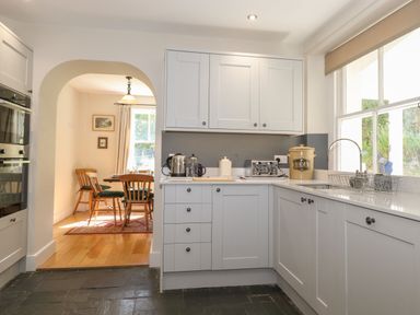 A kitchen with white cabinets, countertop appliances, and a washing area next to a window at High Stile in Seatoller near Rosthwaite