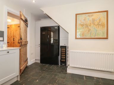 A kitchen area with a black refrigerator under stairs a wooden door and a wall map at High Stile Seatoller near Rosthwaite