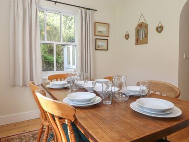 A dining room with a wooden table set with bowls plates glasses and a jug at High Stile in Seatoller near Rosthwaite