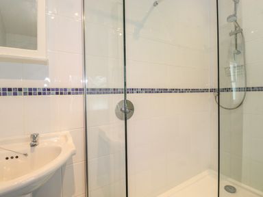 A bathroom with a sink and a walk-in shower with glass panels and a showerhead at High Stile in Seatoller near Rosthwaite