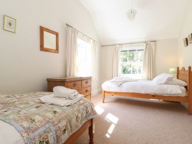 A bedroom with two single beds wooden dresser and windows with curtains at High Stile in Seatoller near Rosthwaite