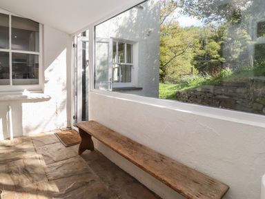 A hallway with a wooden bench stone floor large window and glass door opening to a garden at High Stile in Seatoller near Rosthwaite