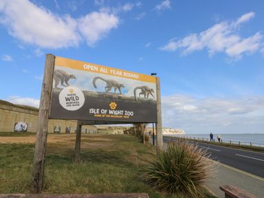 A roadside sign for Isle of Wight Zoo with a blue sky and sea in the background at Nanny's Little House in Sandown