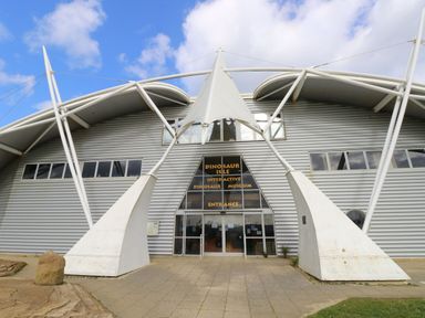 Front entrance of Dinosaur Isle interactive dinosaur museum with metal structure and glass doors at Nanny's Little House in Sandown