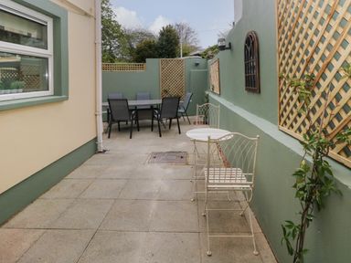 An outdoor patio area with two metal chairs and a small round table and a larger dining table with six chairs at Stones Throw in Tenby